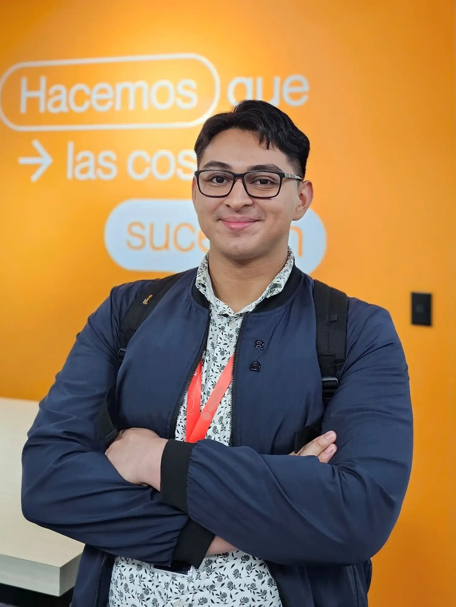 Esteban Alvarenga sonriendo con una chaqueta azul y gafas en la oficina